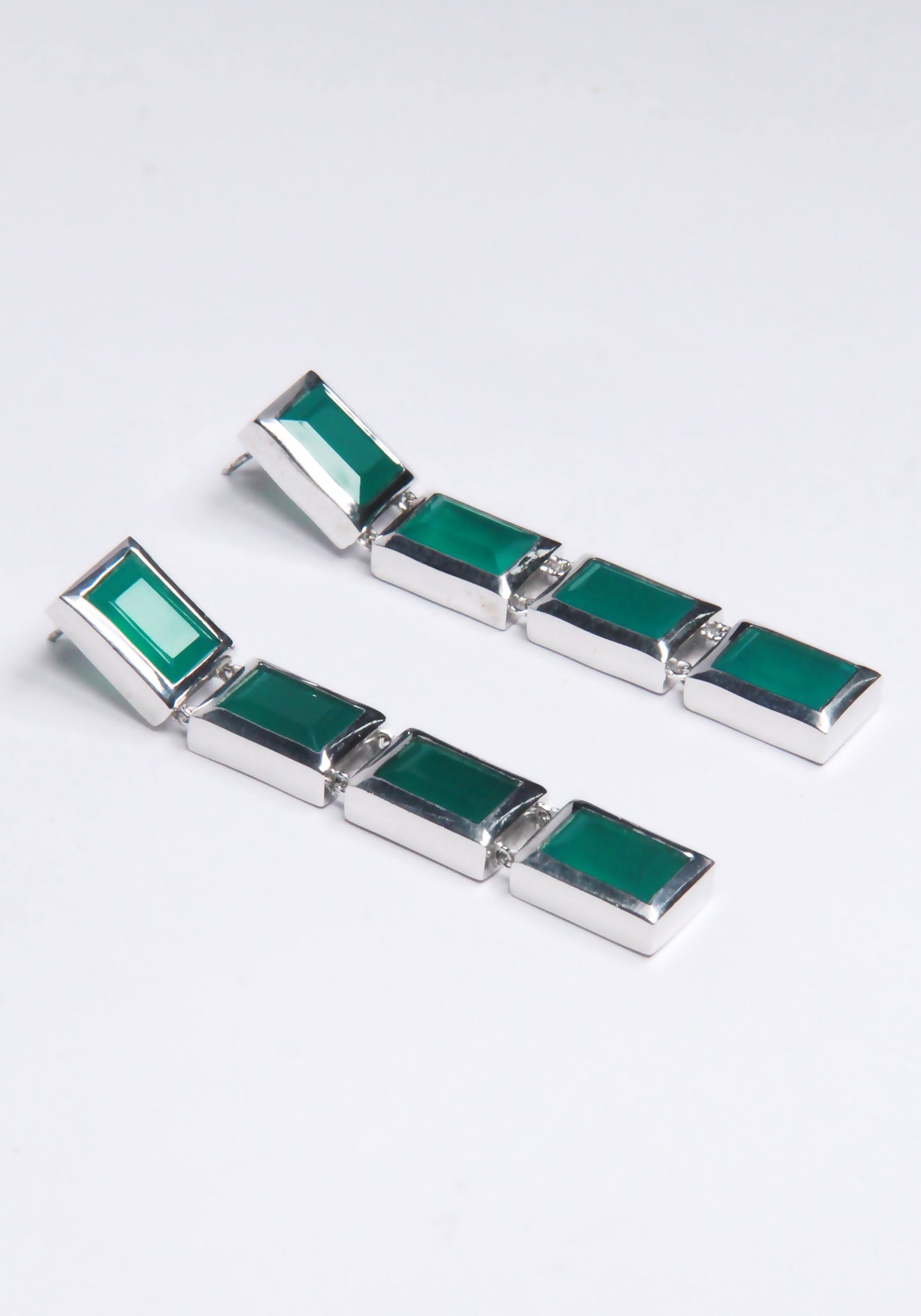 A pair of drop earrings with green gemstones, displayed against a white background.