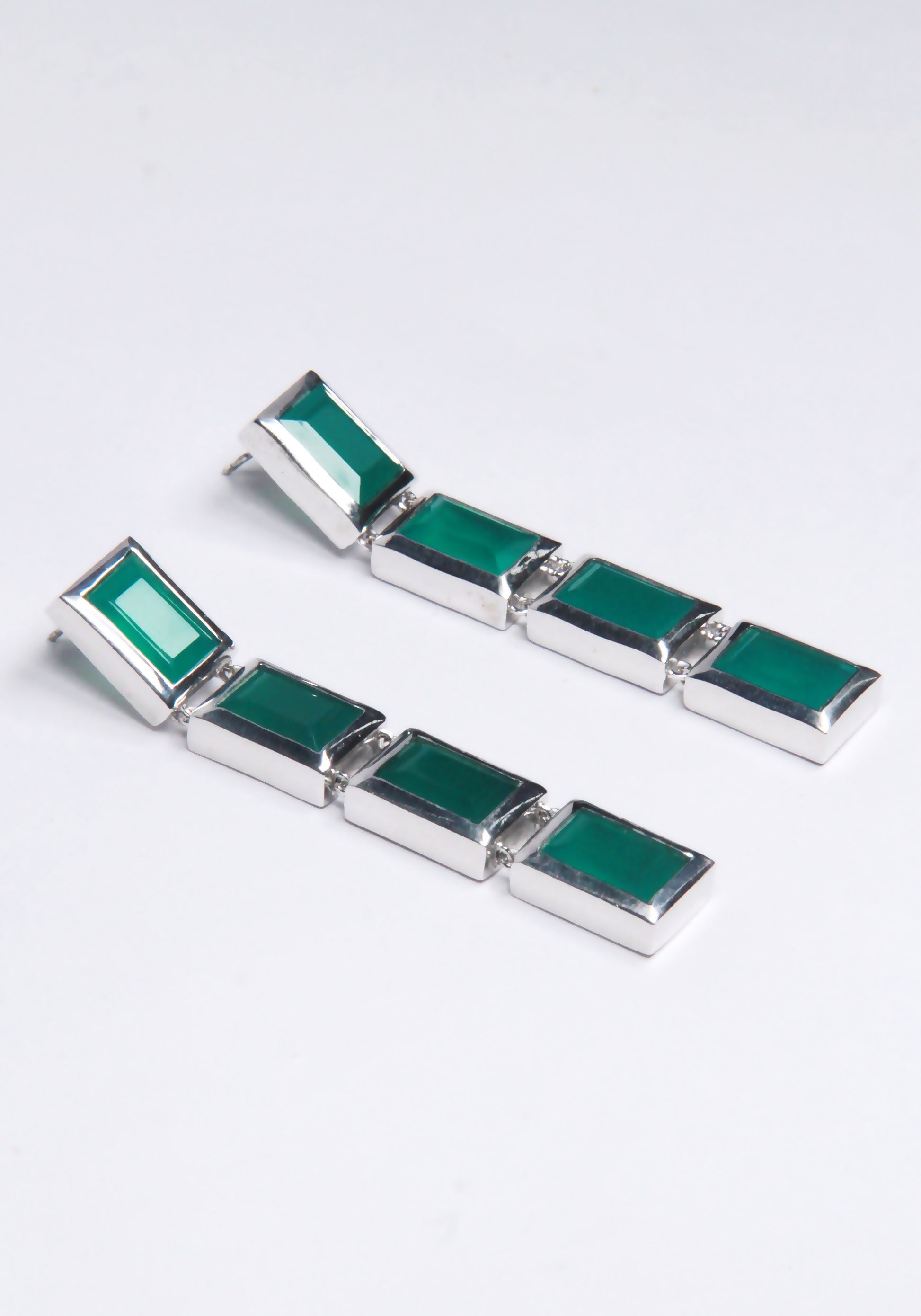 A pair of drop earrings with green gemstones, displayed against a white background.